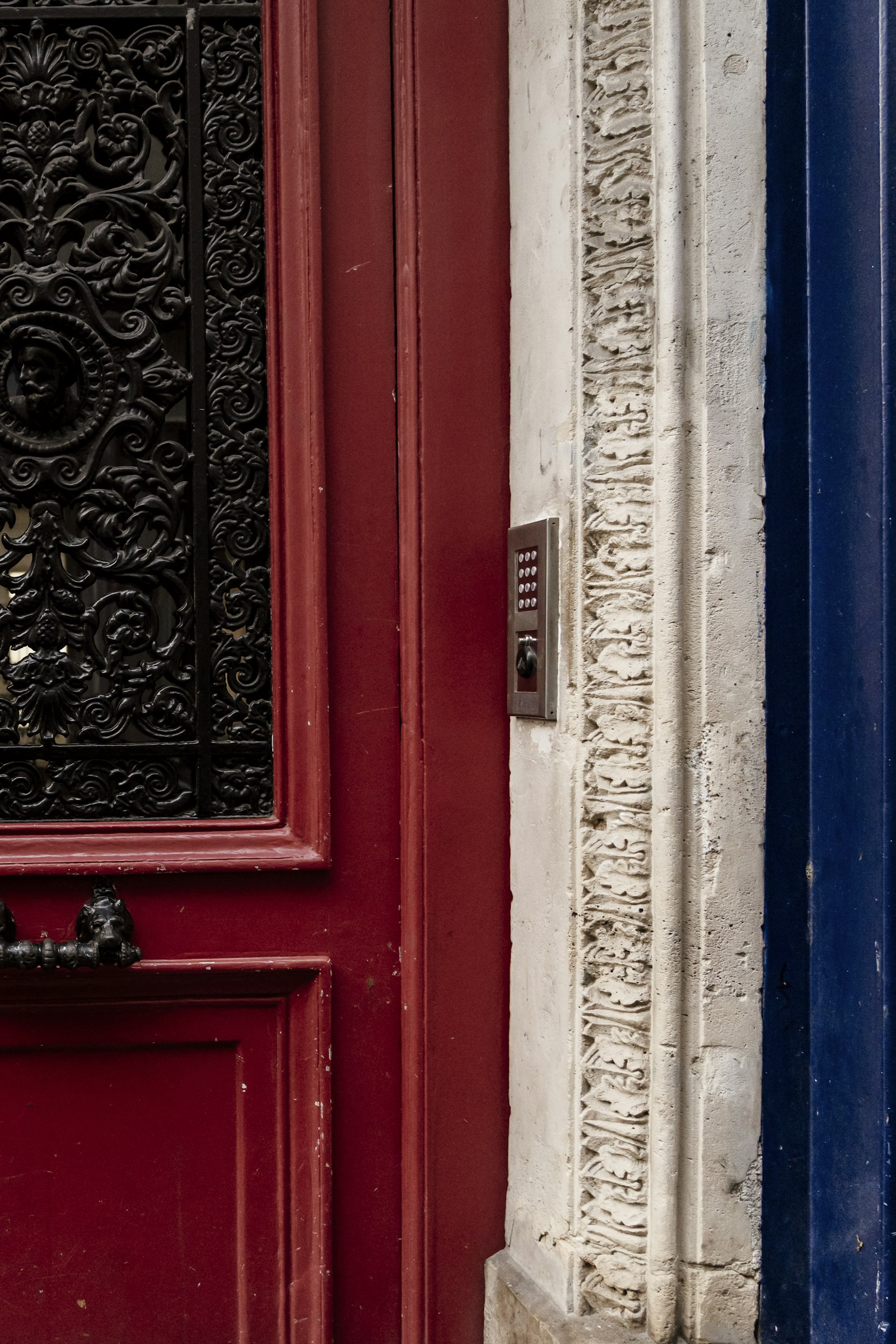 A red Parisian door framed in blue stone