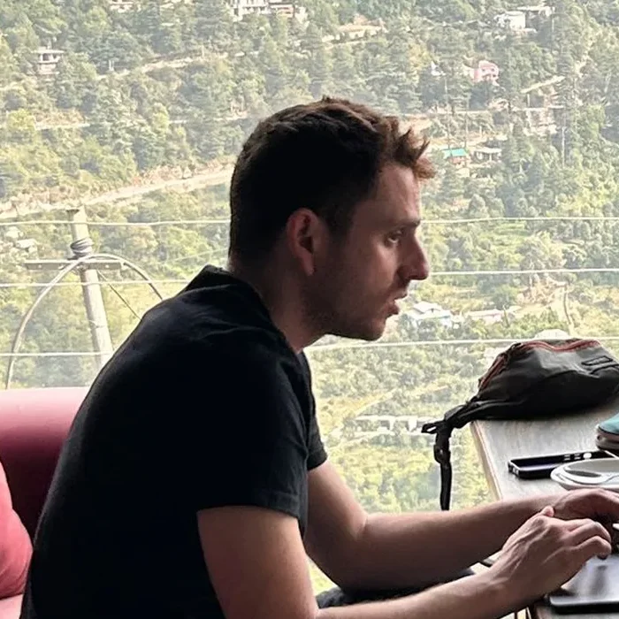 Yann working on his laptop in a cafe, mountain view behind him