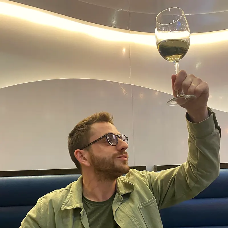 Yann Darmon holding a glass of white wine up to the light